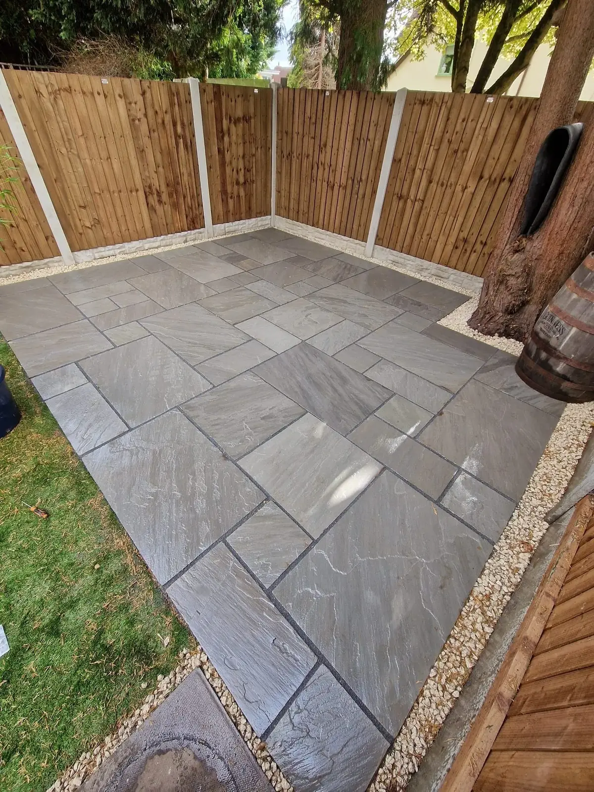 Grey sandstone patio with gravel edge in a fenced Solihull garden