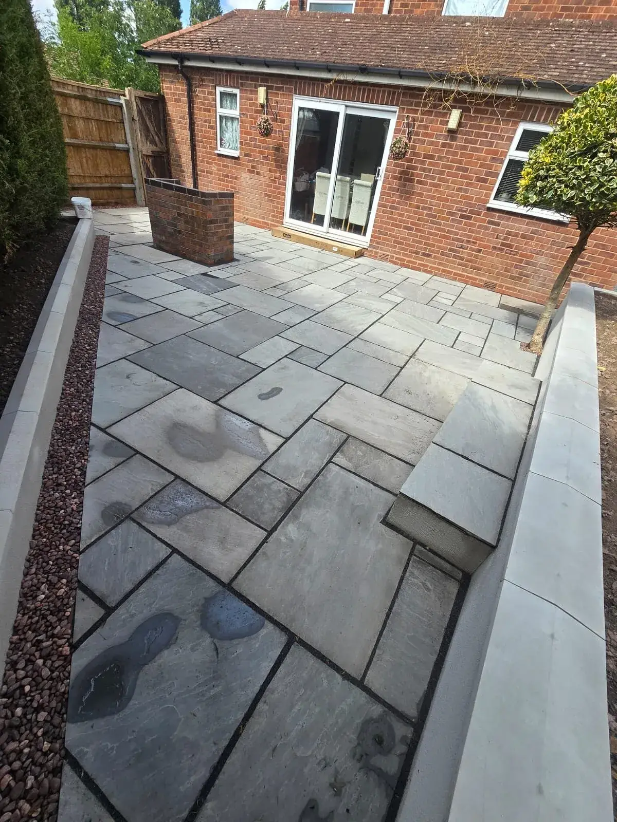 Grey sandstone patio with rendered raised walls at a Solihull property