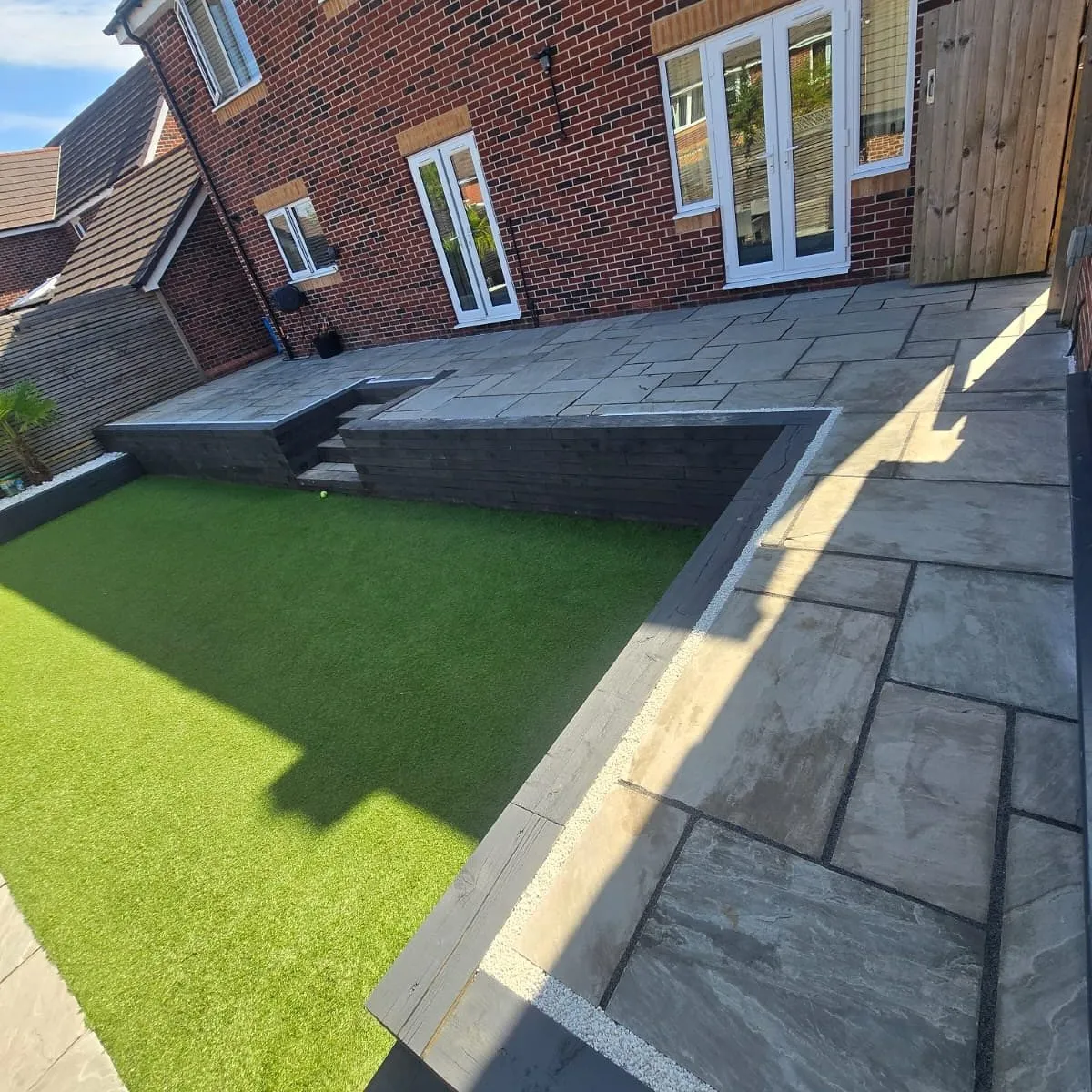 Garden landscaping in Solihull with raised sandstone patio and artificial grass