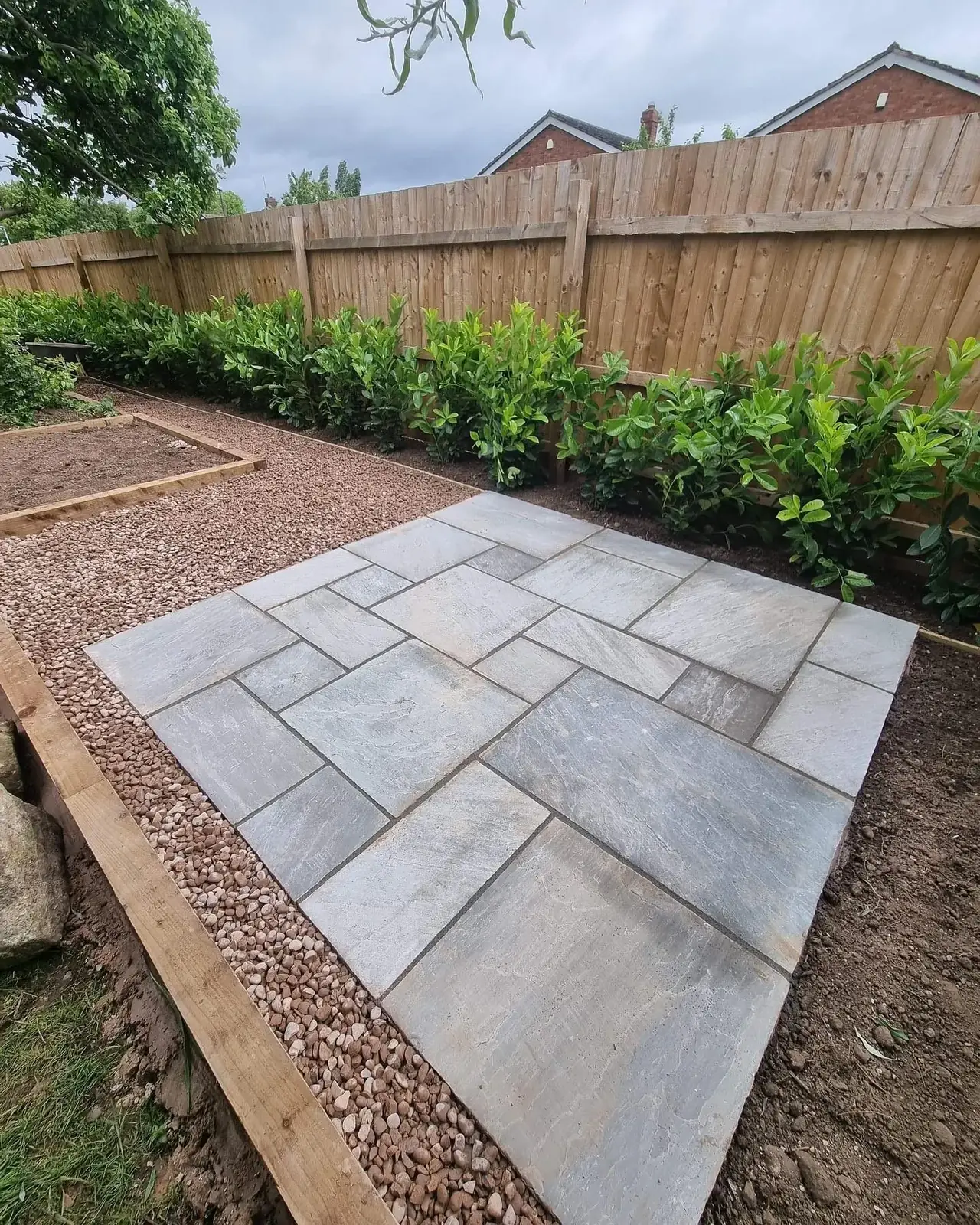 Grey sandstone patio laid beside gravel path and new fence in a Solihull garden