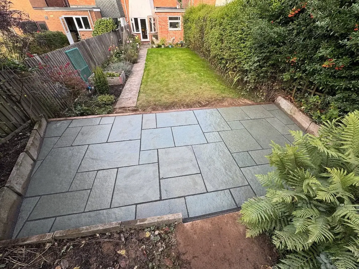 Grey stone patio at the end of a lawn in a Solihull back garden