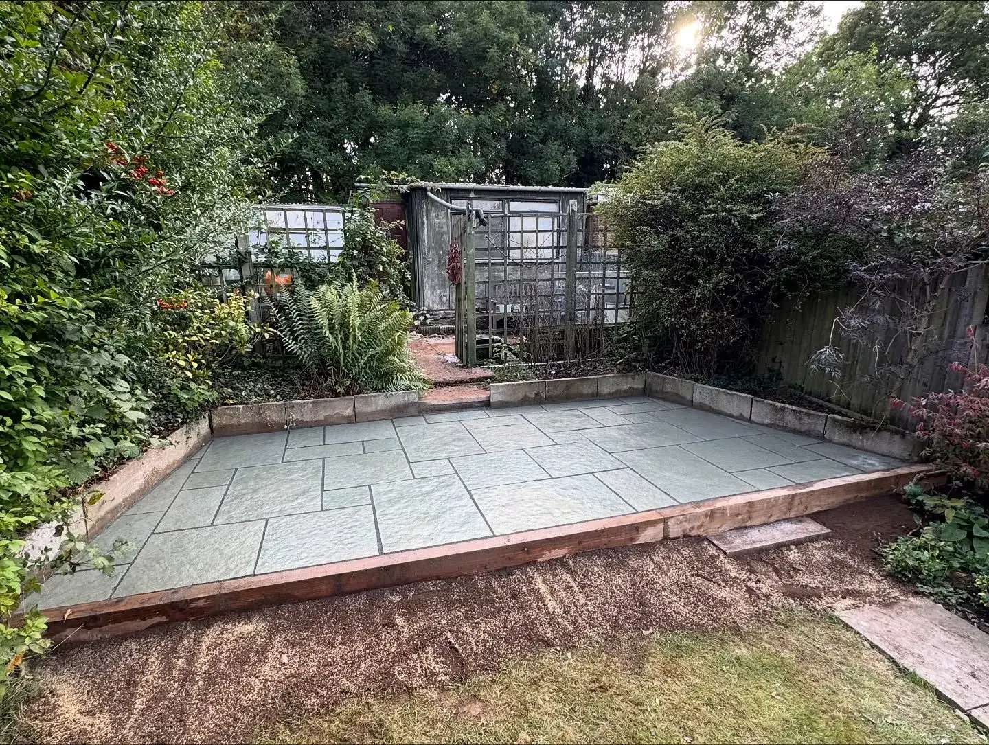 Grey slate-effect patio framed with timber sleepers in a Solihull garden