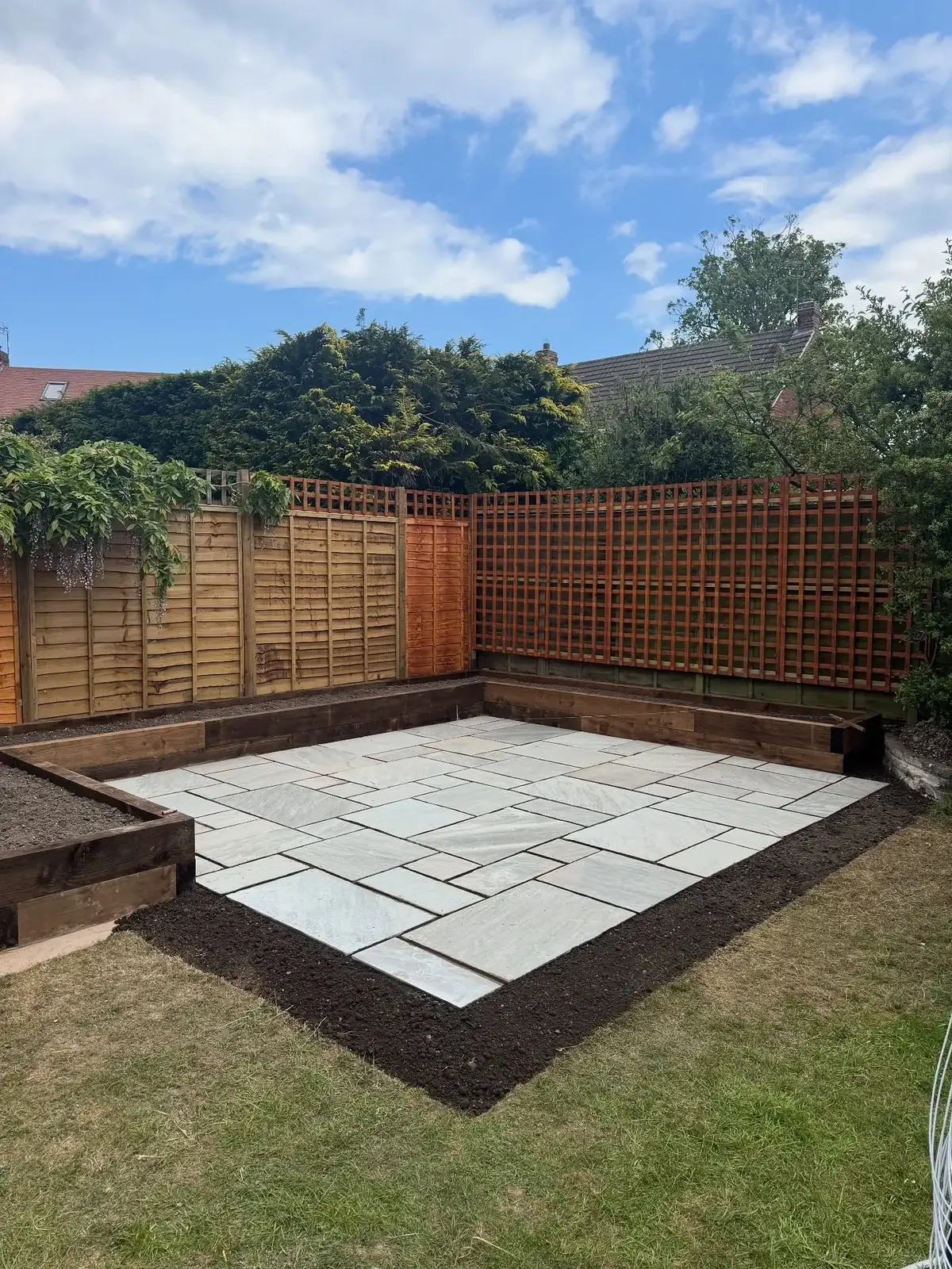 Sandstone patio with sleeper edging and trellis fencing in a Solihull garden