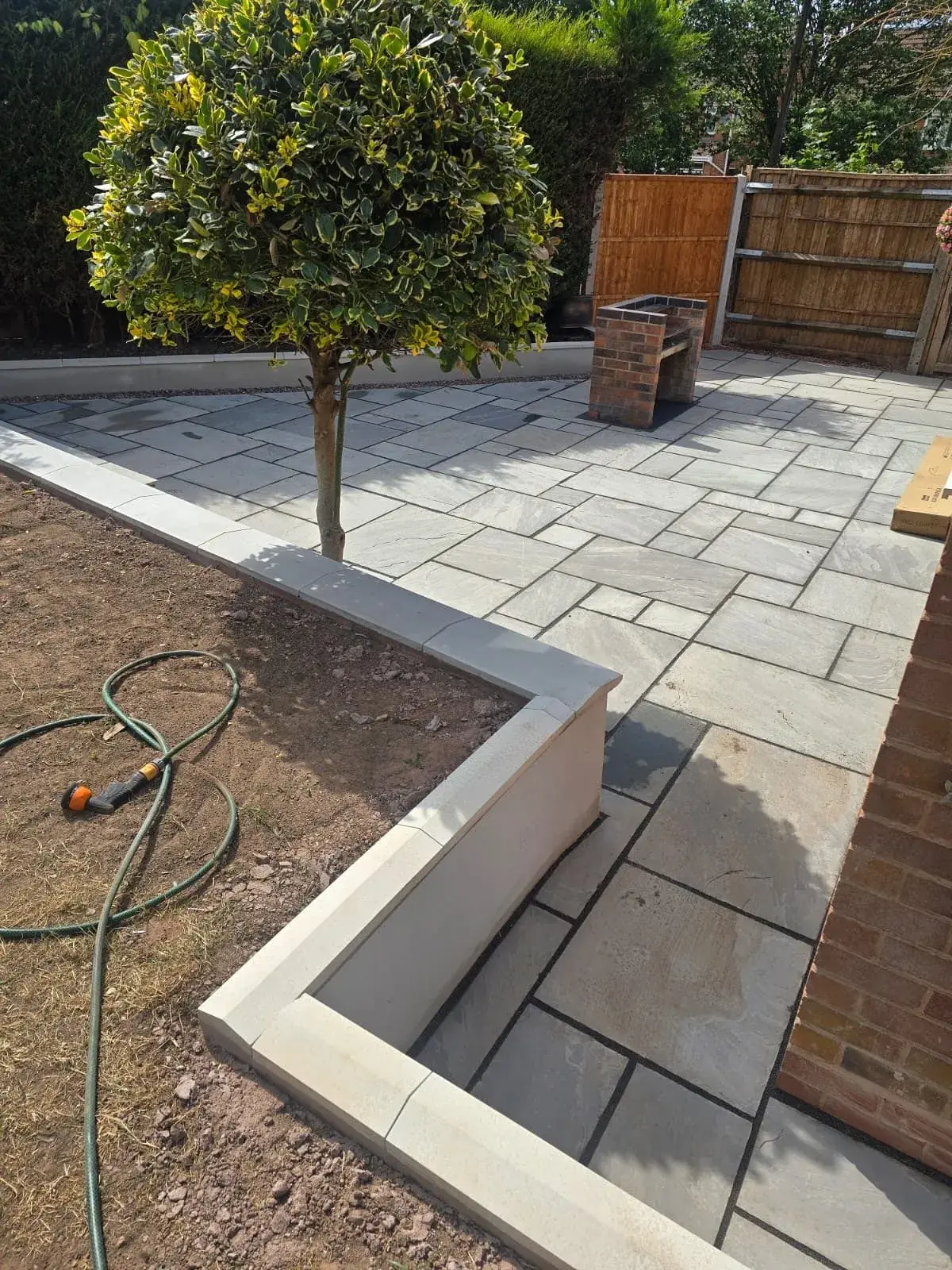 Sandstone patio with rendered raised planter wall in Solihull