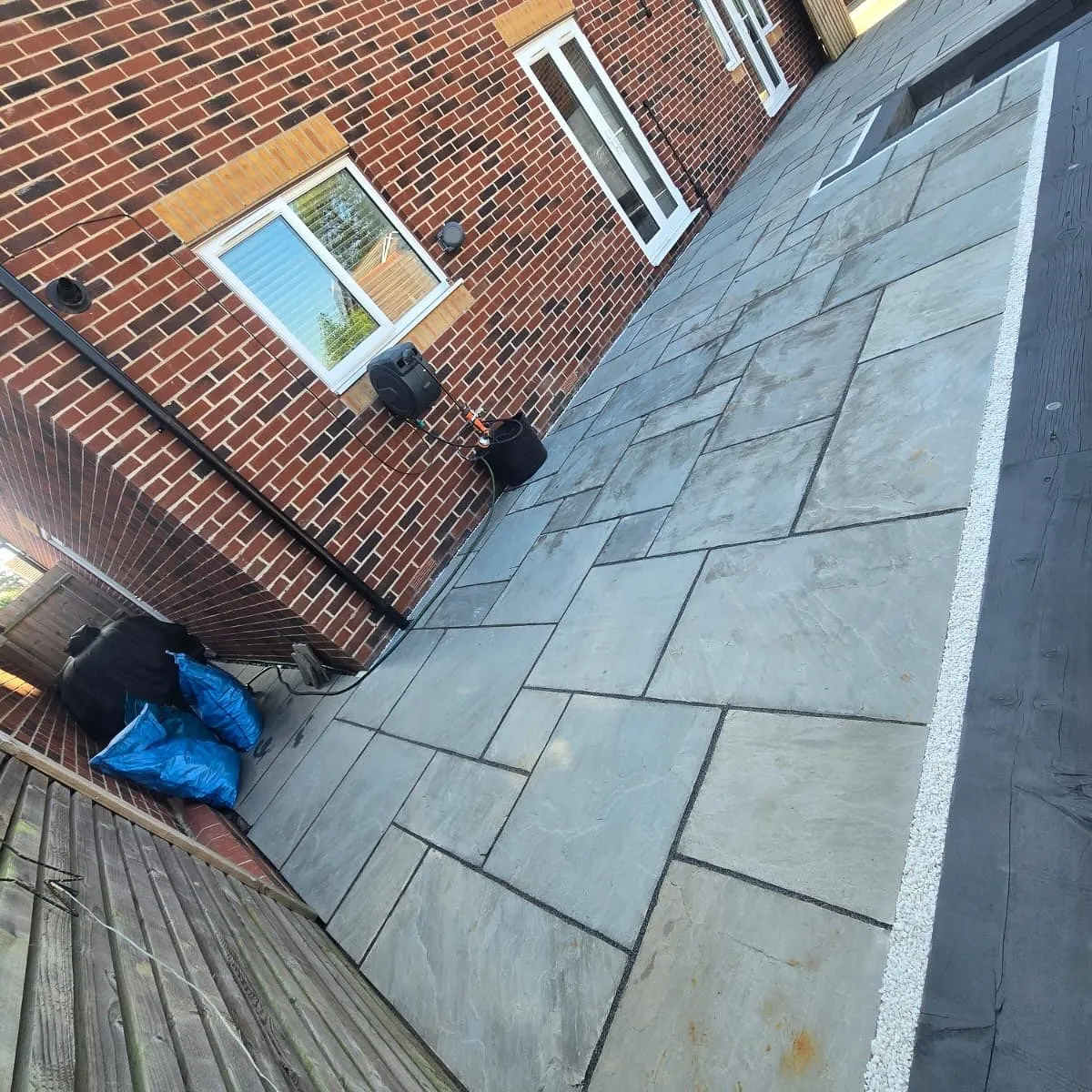 Grey sandstone patio running along the side of a brick house in Solihull