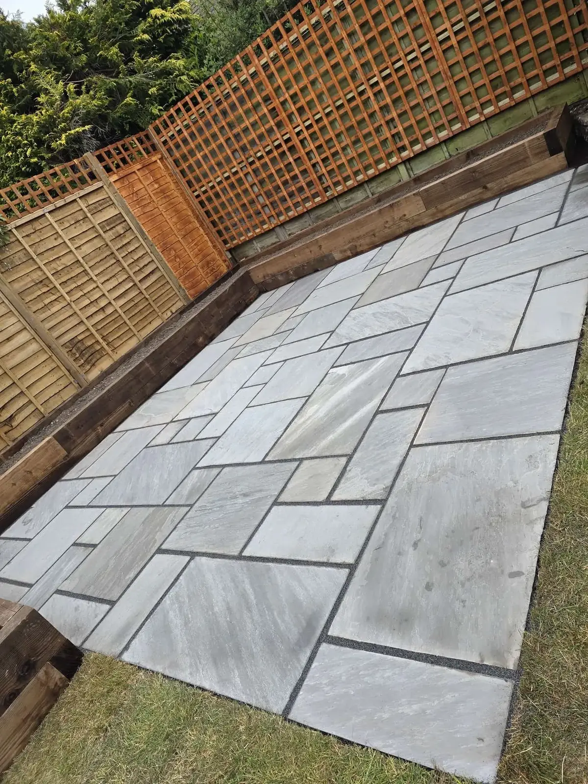 Indian sandstone patio edged with timber sleepers in Solihull