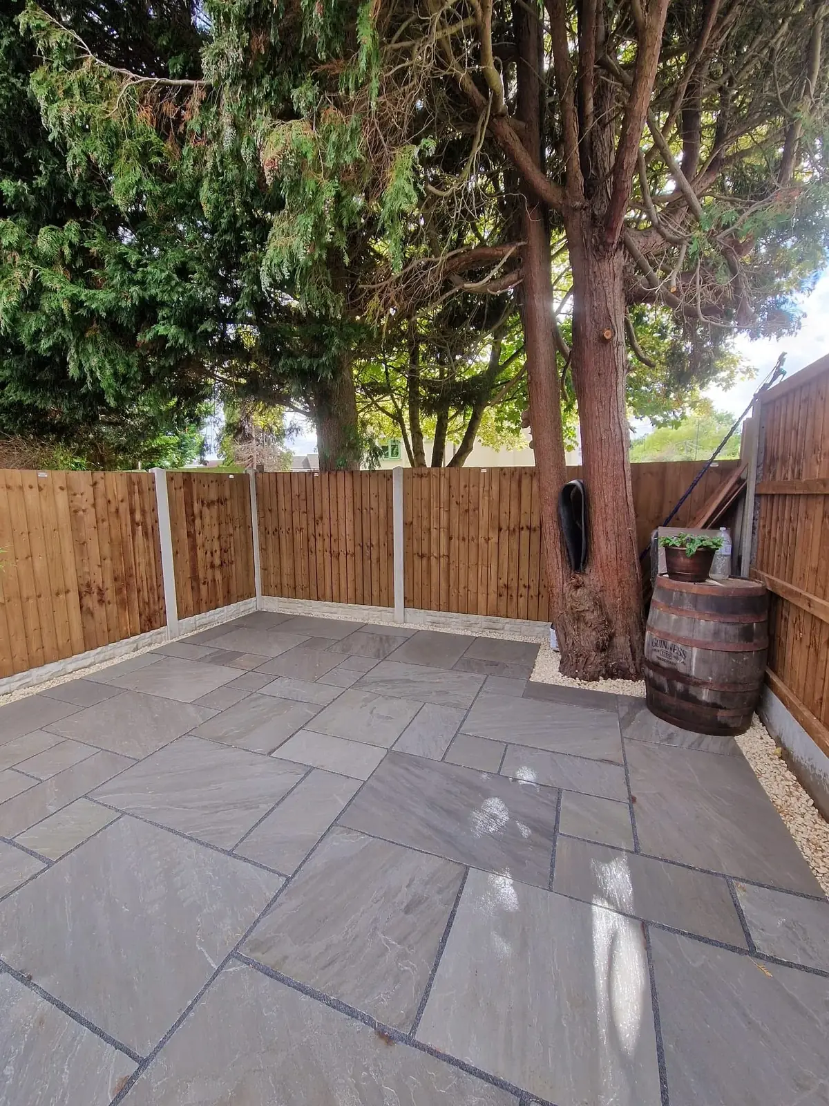 Grey sandstone patio around a mature tree with new fencing in Solihull